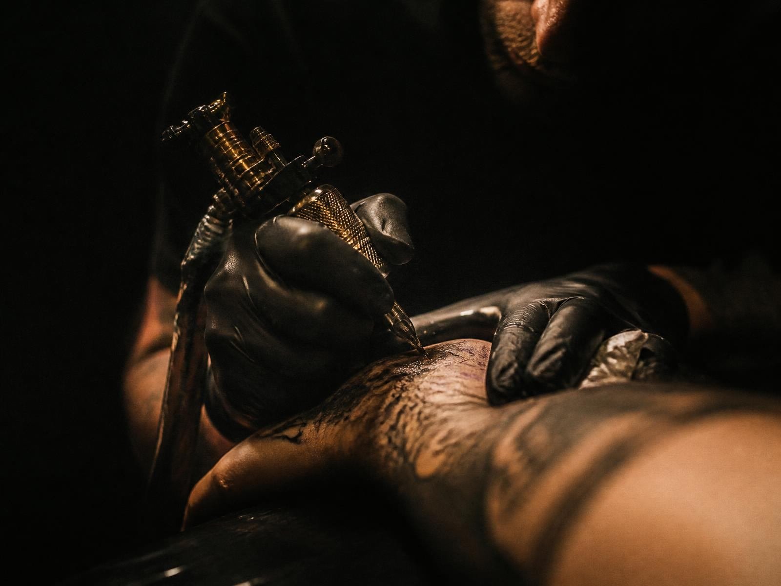 Tattoo artist working with a machine under low studio light